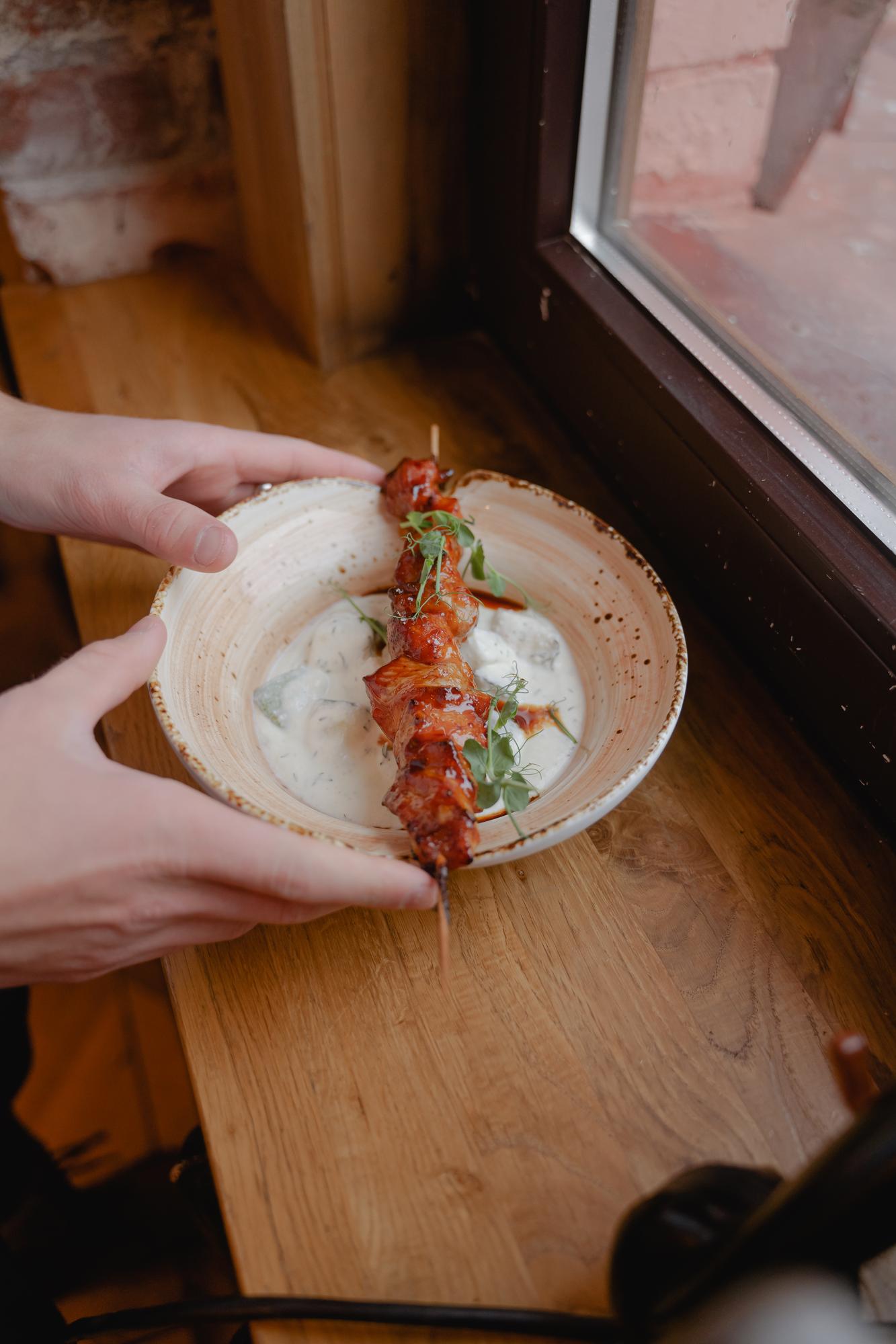 hands plating a rustic dish on paper-like surface